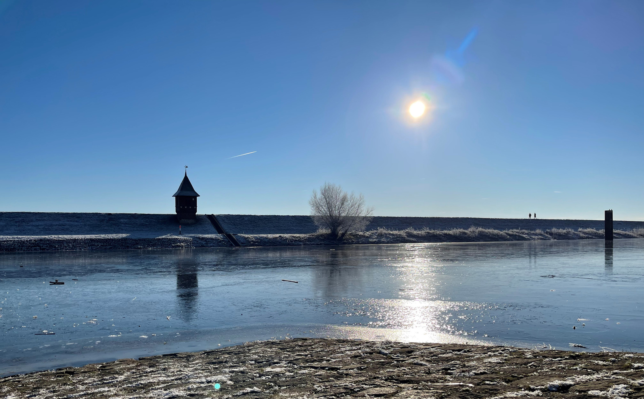 Elbe in tangermünde im Winter. Die Sonne scheint, man siehr das Pegelhäuschen auf dem Deich.