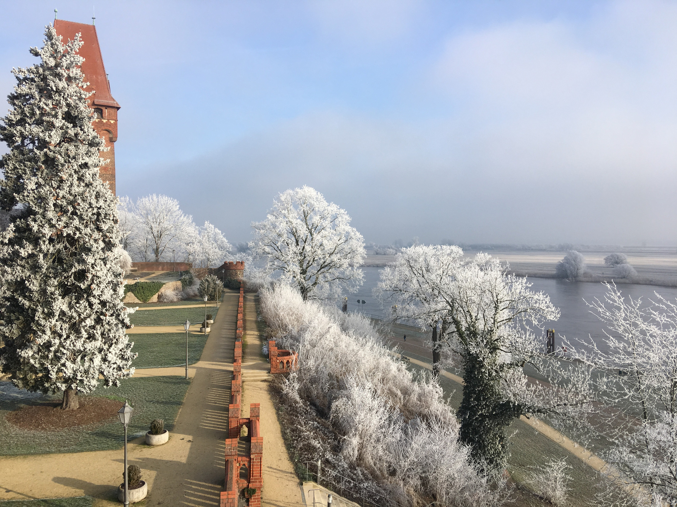 Burgberg von Tangermünde im Winter. Reif liegt auf dem Bäumen und man sieht den Kapitelturm sowie die Elbe.